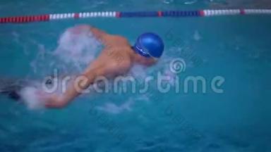 一个人在游泳池里游泳。 上景。 蓝色的水。 蓝色帽子。 运动员。 游泳。